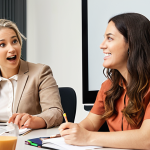 ** A diverse team actively engaged in a "Lunch and Learn" session, with one member presenting enthusiastically on a topic while others listen attentively, some taking notes, showcasing a culture of shared knowledge and continuous learning.

**